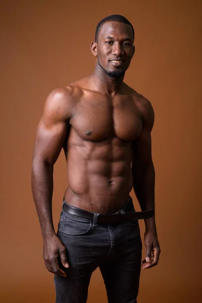 Yakışıklı kaslı Afrika adam kahverengi arka planı gömleksiz