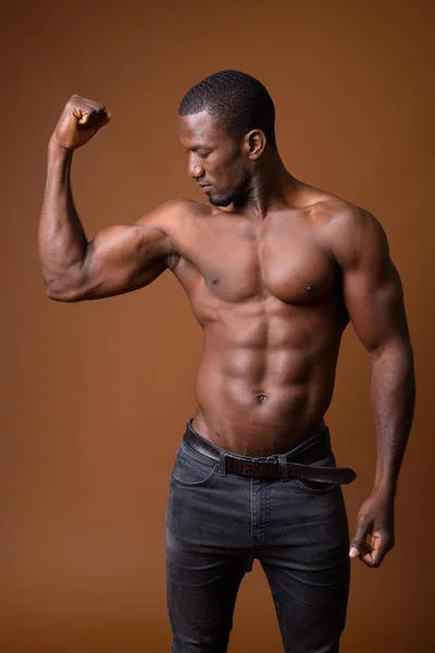 Hombre africano musculoso guapo sin camisa sobre fondo marrón —  Fotos de Stock