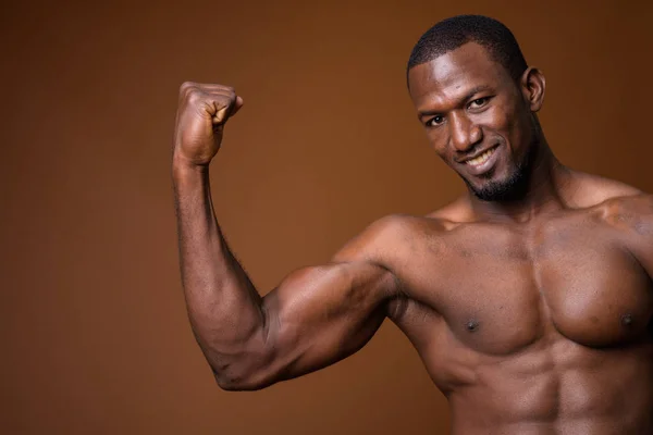 Hombre africano musculoso guapo sin camisa sobre fondo marrón — Foto de Stock