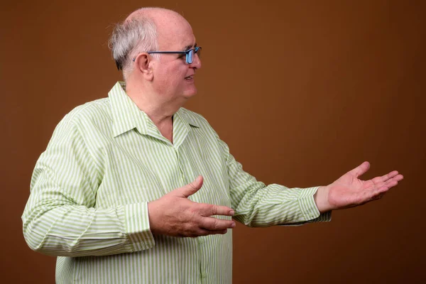 Överviktiga äldre mannen bär glasögon mot brun bak — Stockfoto