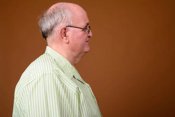 Starszy człowiek, noszenie okularów przeciwko deseń brązowy z nadwagą — Zdjęcie stockowe