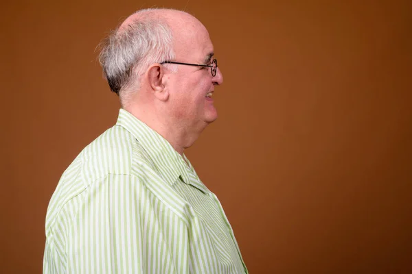 Толстый мужчина в очках против коричневой спинки — стоковое фото