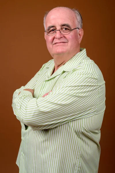 Старший чоловік надмірної ваги носить окуляри на коричневому фоні — стокове фото