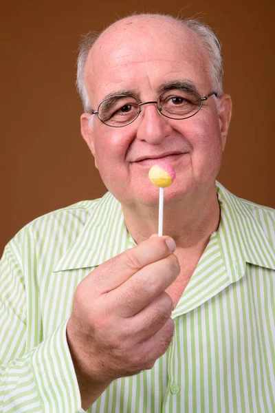 Uomo anziano sovrappeso che indossa occhiali contro backgroun marrone — Foto Stock