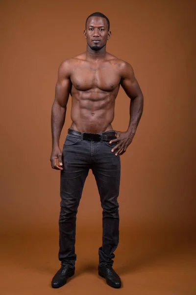 Handsome muscular African man shirtless against brown background — Stock Image Handsome muscular African man shirtless against brown background Royalty Free Stock Images