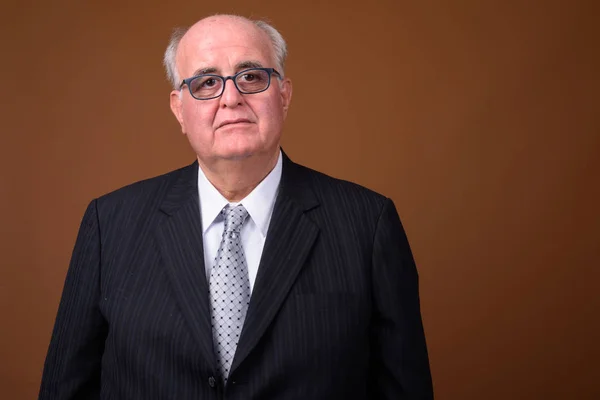 Overweight senior businessman wearing eyeglasses against brown b — Stock Photo, Image