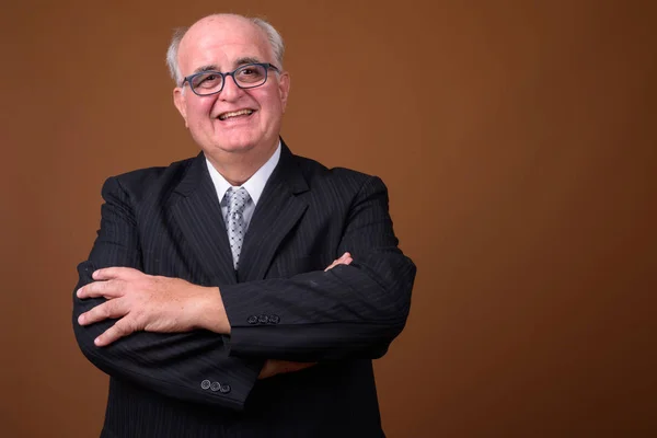 Överviktiga äldre affärsman som bär glasögon mot brun b — Stockfoto