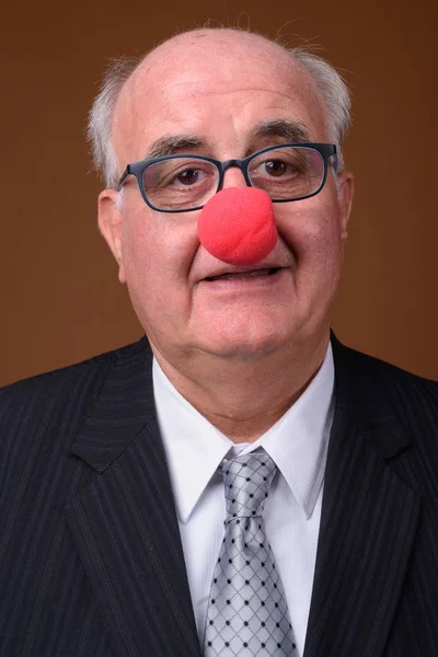 Overweight senior businessman wearing red clown nose