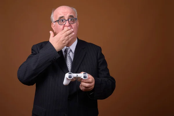 Overweight senior businessman playing games and holding game controller — Stock Photo, Image