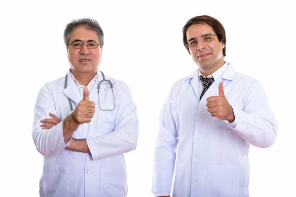 Studio shot of young and senior Persian man doctor giving thumb — Stock Photo, Image