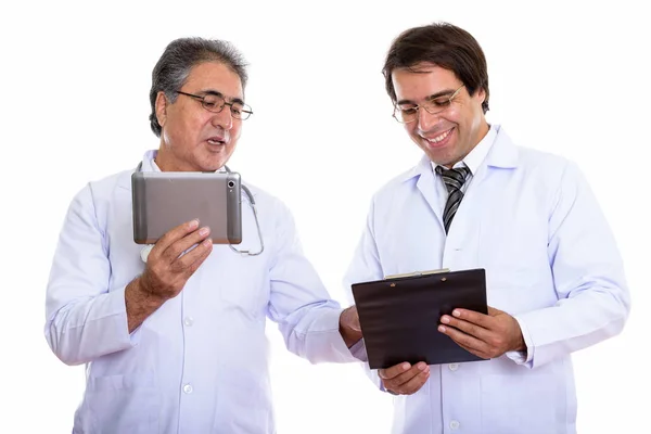 Studio shot of happy young and senior Persian man doctor smiling Stock Image