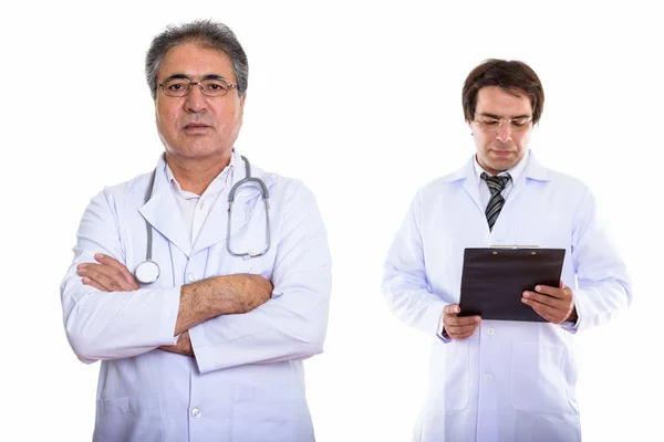 Studio shot of senior Persian man doctor with arms crossed and y — Stock Photo, Image