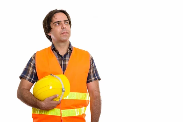 Studio shot of young Persian man construction worker thinking wh — Stock Photo, Image