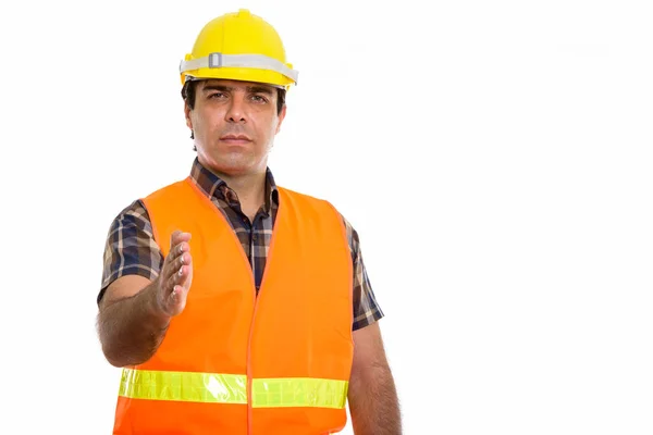 Studio shot of young Persian man construction worker giving hand — Stock Photo, Image