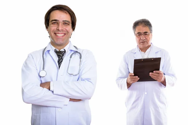 Young happy Persian man doctor smiling with arms crossed and sen Stock Image