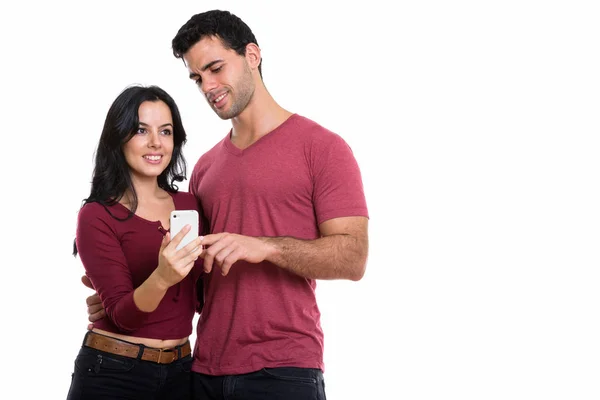Студійний знімок молодої щасливої пари, яка посміхається з чоловіком, використовуючи мобільний — стокове фото