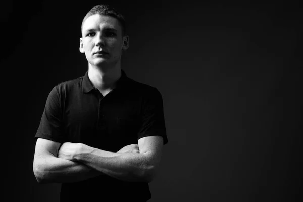 Junger Mann vor schwarzem Hintergrund in schwarz-weiß — Stockfoto