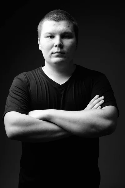 Übergewichtiger junger Mann vor schwarzem Hintergrund in schwarz-weiß — Stockfoto
