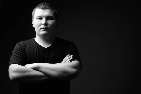 Overgewicht jongeman tegen zwarte achtergrond in zwart-wit — Stockfoto
