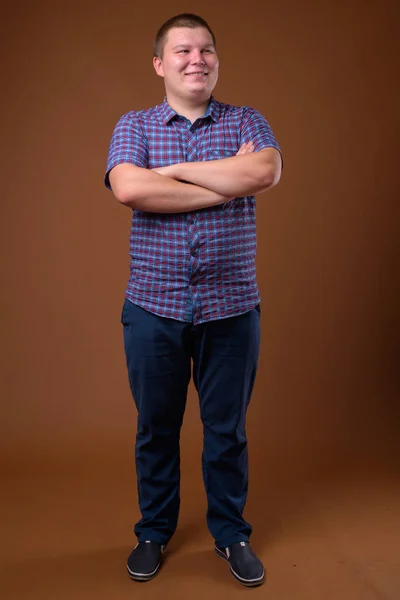 Studio shot of overweight young man against brown background Royalty Free Stock Photos