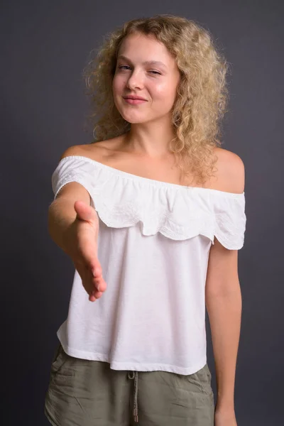 Jovem mulher bonita com cabelo encaracolado loiro contra backgro cinza — Fotografia de Stock