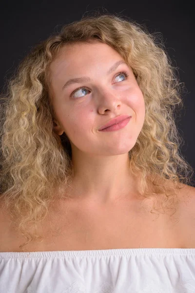 Joven hermosa mujer con el pelo rubio rizado contra el backgro gris —  Fotos de Stock