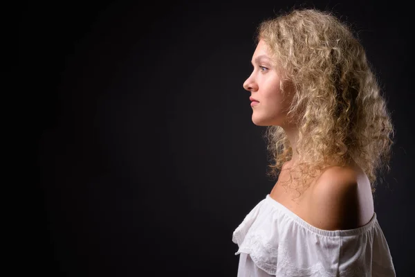 Young beautiful woman with blond curly hair against gray backgro — Stock Photo, Image