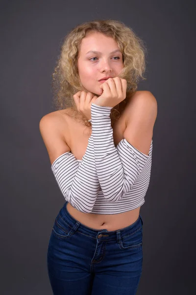 Jovem mulher bonita com cabelo encaracolado loiro contra backgro cinza — Fotografia de Stock