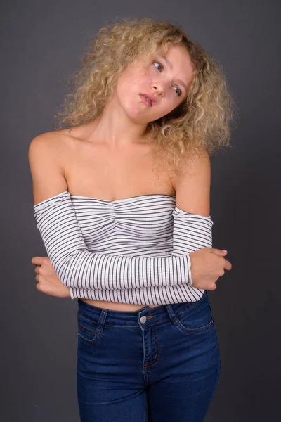 Young beautiful woman with blond curly hair against gray backgro — Stock Photo, Image