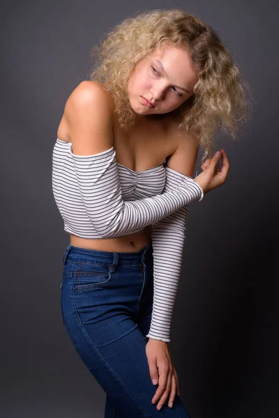 Jeune belle femme aux cheveux bouclés blonds sur fond gris — Photo