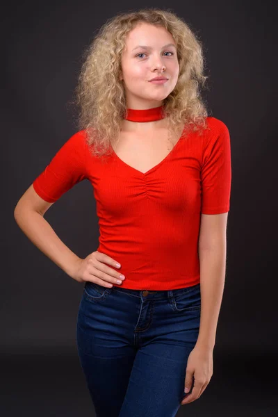 Jovem mulher bonita com cabelo encaracolado loiro contra backgro cinza — Fotografia de Stock
