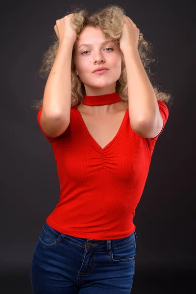 Młoda kobieta piękne blond włosy kręcone przeciwko szary backgro — Zdjęcie stockowe