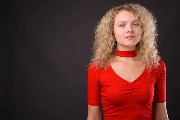 Joven hermosa mujer con el pelo rubio rizado contra el backgro gris — Foto de Stock