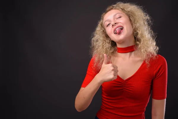 Jovem mulher bonita com cabelo encaracolado loiro contra backgro cinza — Fotografia de Stock