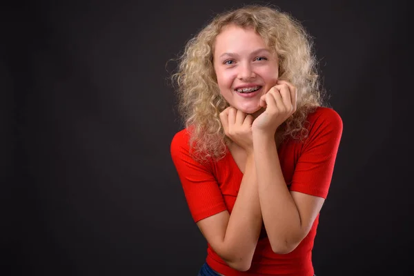 Mooie jongedame met blond krullend haar tegen grijs backgro — Stockfoto