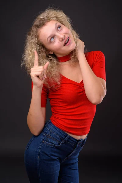 Joven hermosa mujer con el pelo rubio rizado contra el backgro gris —  Fotos de Stock