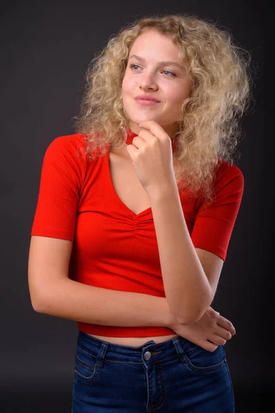 Молода красива жінка з світлим кучерявим волоссям на сірому фоні — стокове фото