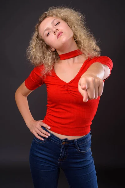 Mooie jongedame met blond krullend haar tegen grijs backgro — Stockfoto