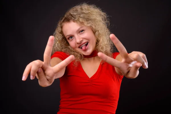 Mooie jongedame met blond krullend haar tegen grijs backgro — Stockfoto