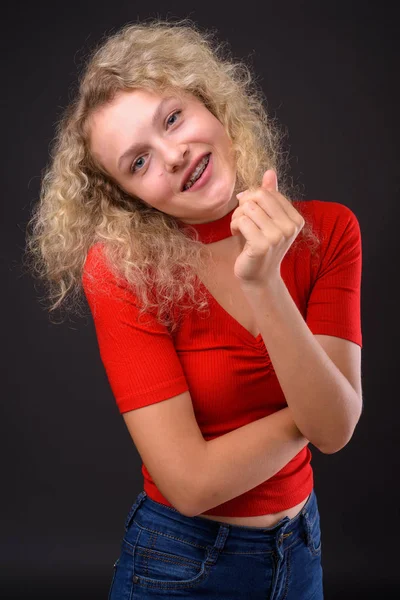 Joven hermosa mujer con el pelo rubio rizado contra el backgro gris —  Fotos de Stock