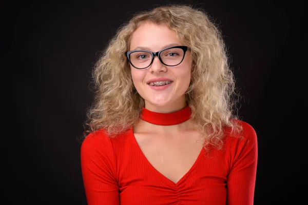 Jeune belle femme aux cheveux bouclés blonds sur fond gris — Photo