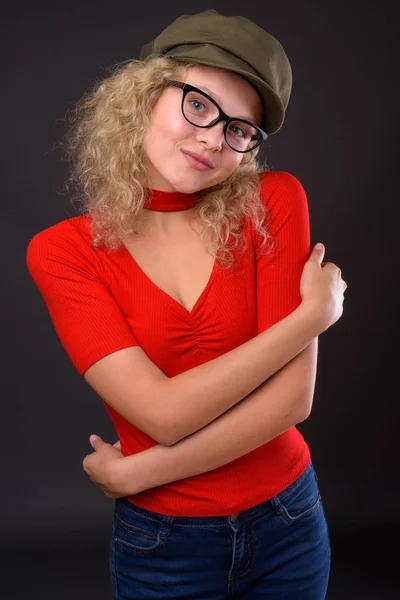 Mooie jongedame met blond krullend haar tegen grijs backgro — Stockfoto