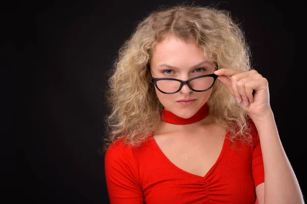 Young beautiful woman with blond curly hair against gray backgro Stock Image