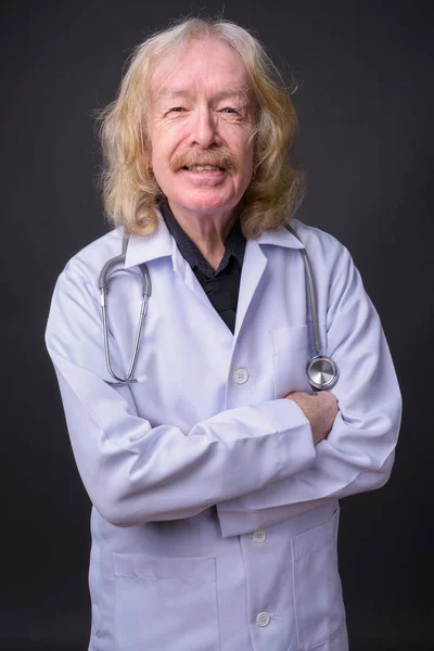 Senior man läkare med mustasch mot grå bakgrund — Stockfoto