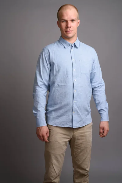 Glatzköpfiger Geschäftsmann mit blauem Hemd vor grauem Hintergrund — Stockfoto
