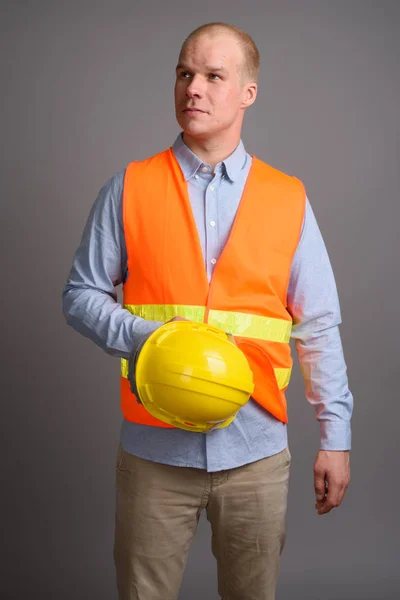 Homem careca trabalhador da construção contra fundo cinza — Fotografia de Stock