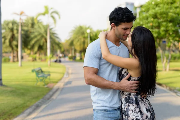 Jovem casal hispânico relaxando no parque juntos — Fotografia de Stock