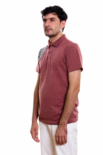 Studio shot of young Persian man standing while thinking and loo — Stock Photo, Image