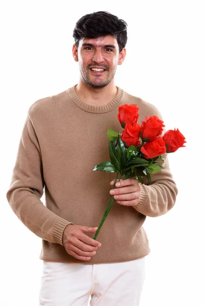 Estudio disparo de joven feliz persa hombre sonriendo mientras sostiene rojo — Foto de Stock