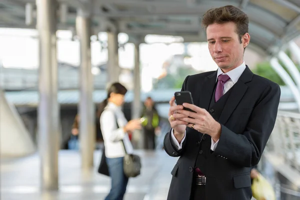 Портрет бизнесмена с помощью мобильного телефона на вокзале — стоковое фото